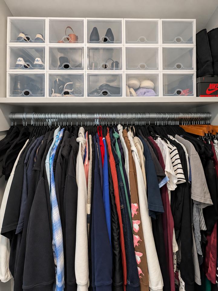 Closet after organizing, with clothes grouped on hangers and accessories separated in clear upper bins