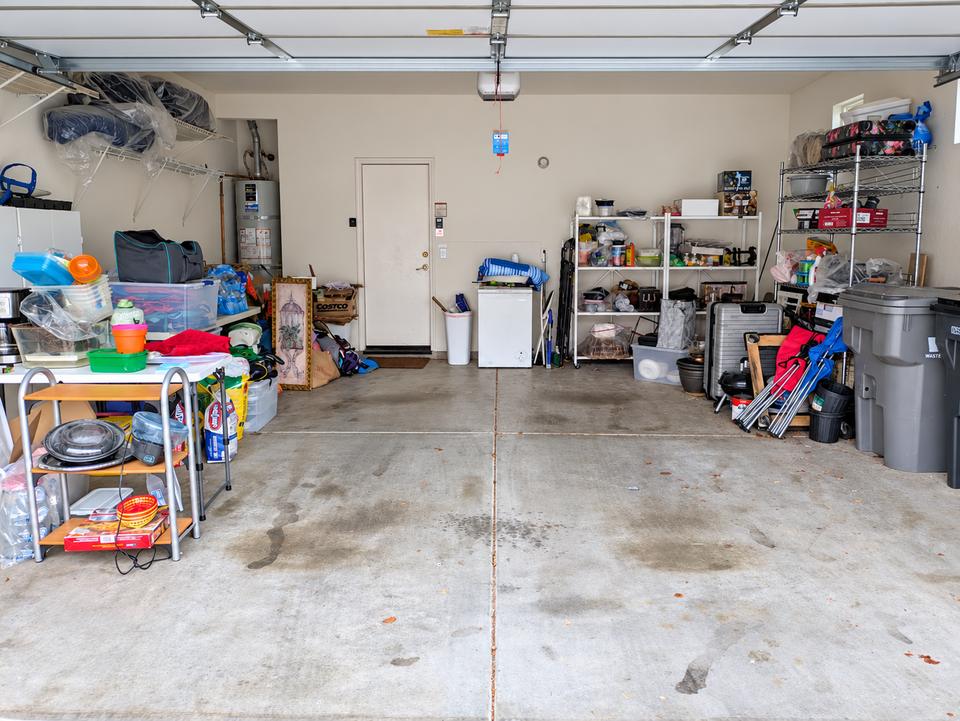 Garage before organizing, with belongings spread around the perimeter and storage shelves