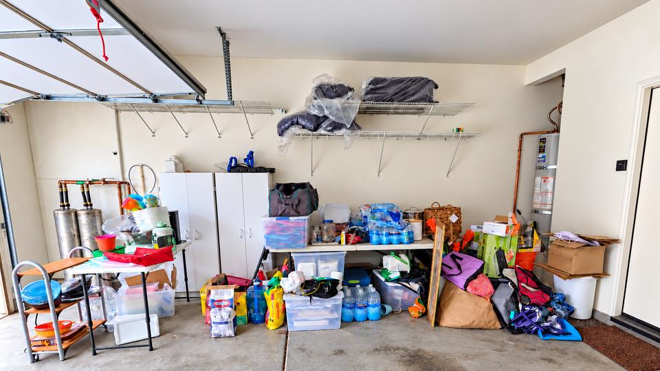 Garage storage wall before organizing, with supplies and belongings spread across the floor