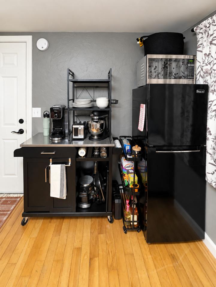 Studio kitchenette after organizing, with a clear floor, compact counter and dedicated appliance shelves